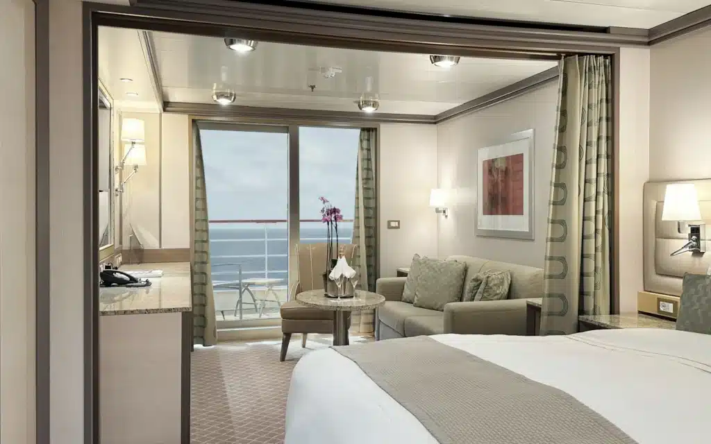 Suite bedroom with sliding doors open to a private balcony and ocean view