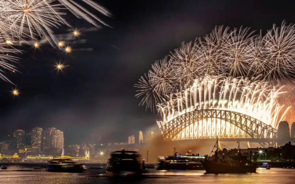 Fireworks burst above the Sydney Harbour Bridge on New Year’s Eve as boats crowd the harbor below