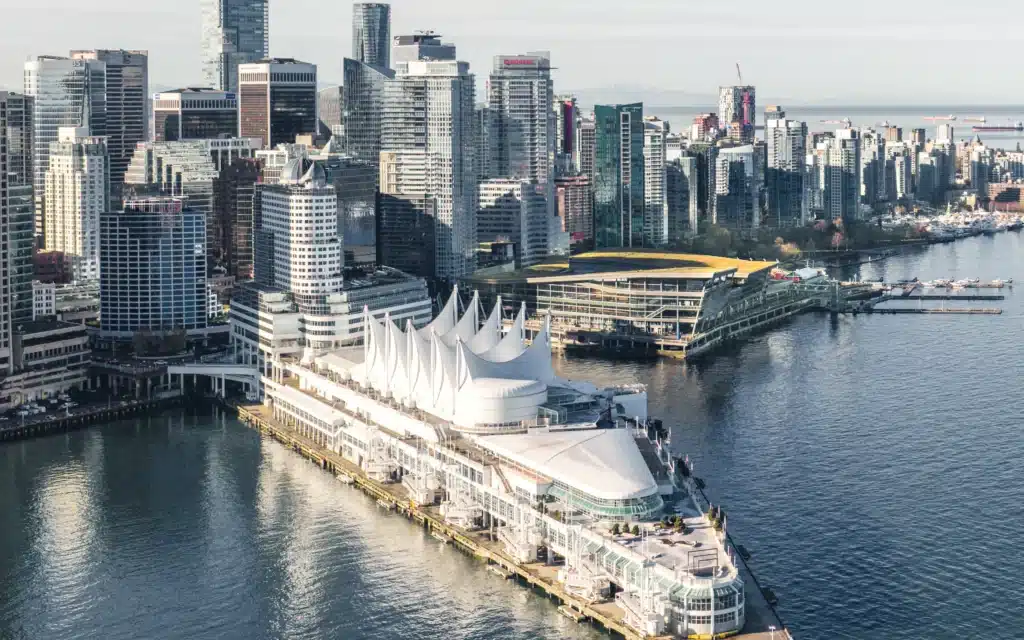 Aerial view of the Canada Place cruise terminal pier extending into Vancouver Harbour, with downtown towers and floatplane docks beyond